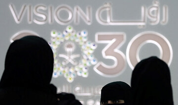 Saudi women stand next to the Saudi pavilion (vision 2030) at the Gitex 2018 exhibition in Dubai. (AFP)