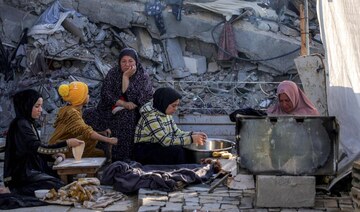 Women prepare food for iftar on the first day of Ramadan, as they sit by the rubble of collapsed building in shelter in Jabalia.