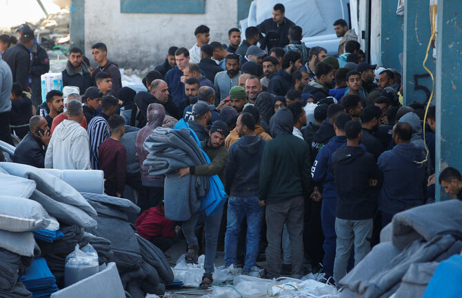 Palestinians gather to receive aid provided by UNRWA including food supplies.