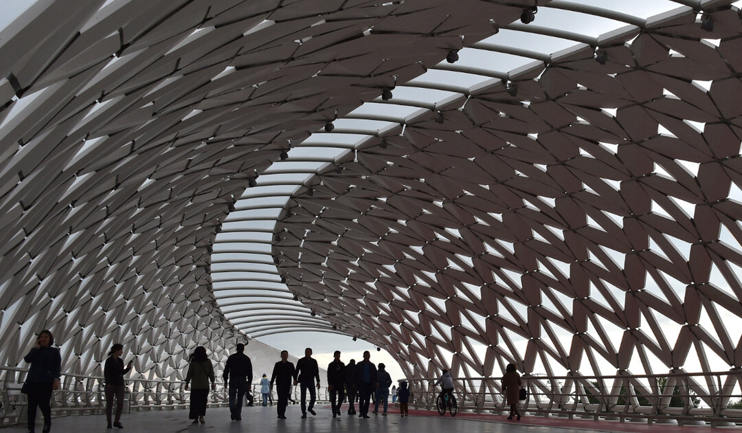 People walk on a bridge over the Ishim river in Nur-Sultan on June 8, 2019. (AFP)